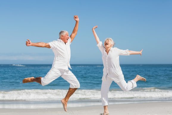 Senior couple jumping at the beach