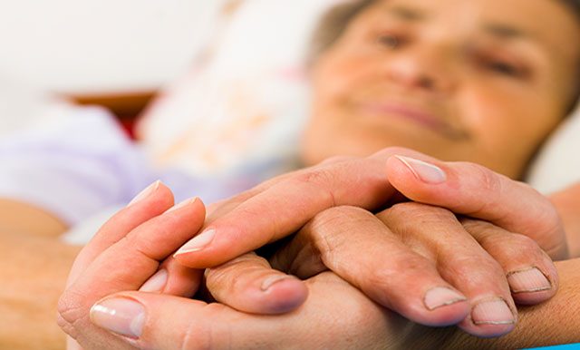 Caregiver and hospice patient holding hands