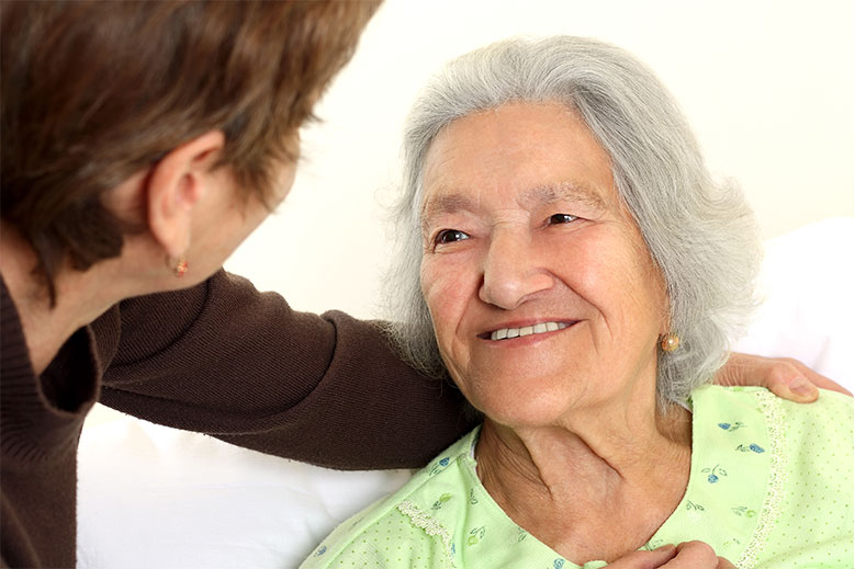 Elderly woman smiling at senior caregiver