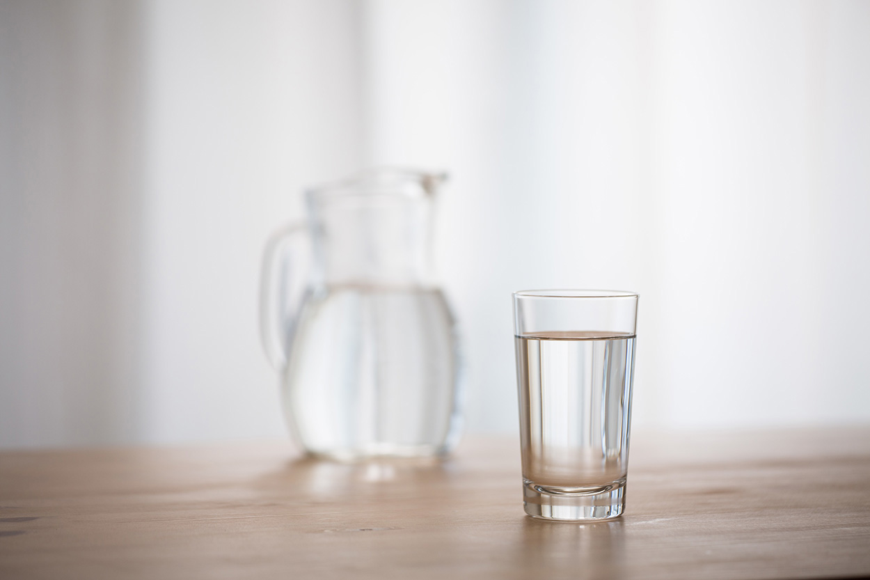 Water pitcher and glass sitting on table